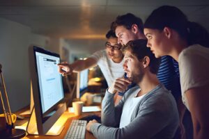 A team of digital marketers reviewing SEO analytics and content performance data on a desktop monitor at night.